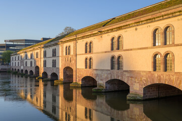 Historic sandstone bridge and weir in Strasbourg, France, showcasing sculptures and architectural beauty from the 17th century