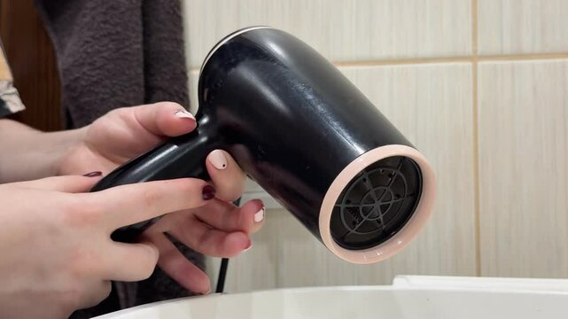 A person angrily hits a non-working hairdryer, expressing frustration due to malfunction. The photo illustrates a common issue with broken home electronics.