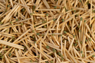 matches with a green head scattered in a large pile, a large number of thin wooden matches with a green head