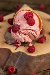 pink ice cream lies on a walnut board, ripe red raspberries and raspberry cold natural ice cream on the table