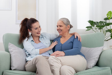 Granddaughter hugs her smiling grandmother with love and joy. Warm and happy family moment at home showing affection, connection, and generational bond between two women in a cozy and peaceful setting