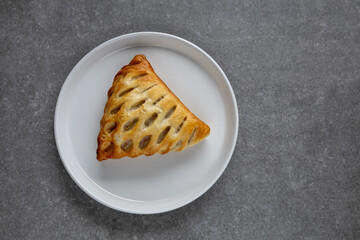 golden puff pastry on white plate with gray surface