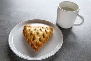 golden puff pastry with milk on white plate and gray surface (side view)