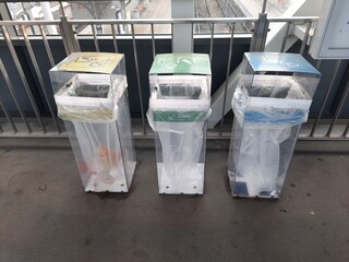 Trzy śmietnika dla segregacji śmieci na papier niebieski, na szkło zielony i na plastik żółty