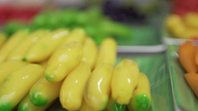Look Choup is a traditional Thai dessert made from sweetened mung bean paste, meticulously shaped into various miniature fruits and vegetables, painted with vibrant colors, and coated in glossy agar g