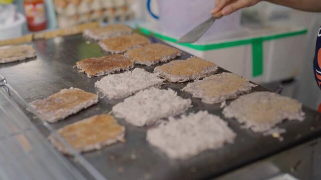 A local vendor is cooking delicious Thai sweet coconut macaroons called Kanom Babin.