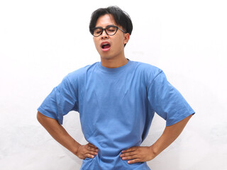 Unhealthy young Asian man with sad and painful expression holding stomach isolated on white...