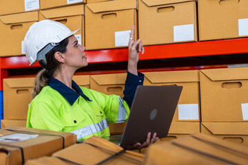 Female warehouse worker smiling while using laptop to shipping manage inventory, working in logistics and supply chain handling import export data, warehouse operations and modern distribution process