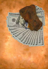 Dollar bills are scattered in a fan on a copper background. Red ochre stone lies on the banknotes....