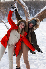Two girls in winter, in warm clothes, enjoying the snow, outdoor. Cold time of the year, laughter and fun. Winter forest, white glade.