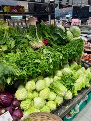 A colorful display of fresh herbs, lettuce, spring onions, and other greens at a local market in...