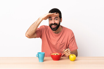 Caucasian man having breakfast in a table looking far away with hand to look something.