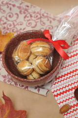 cookies that look like nuts, tied with a bow in a brown ceramic pot. In the background are acorns, maple leaves and a napkin