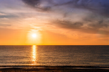 scenic sunrise or sunset above sea water with beautiful ocean vawes , nice golden evening clouds above horizon and awesome blue sky