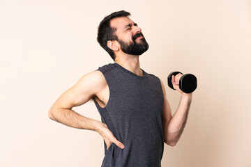 Caucasian sport man with beard making weightlifting over isolated background suffering from...