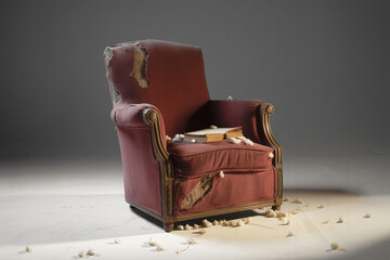 Antique Red Armchair with Worn Fabric and Book Resting on it