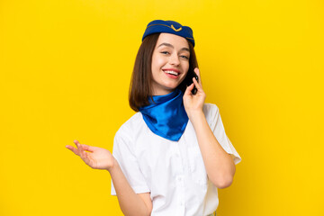 Airplane stewardess Ukrainian woman isolated on yellow background keeping a conversation with the mobile phone with someone
