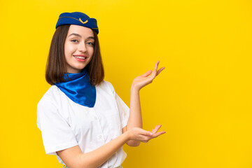 Airplane stewardess Ukrainian woman isolated on yellow background extending hands to the side for inviting to come