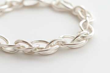 Naklejka premium Elegant close-up of a silver chain bracelet with intricate links on a light background.