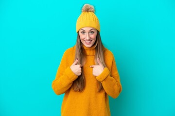 Young caucasian woman wearing winter jacket isolated on blue background with surprise facial expression