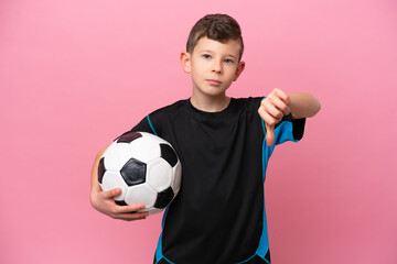 Little caucasian football player boy isolated on pink background showing thumb down with negative...