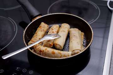 Cooking savory crepes in a frying pan on a stovetop in a modern kitchen during the day