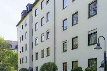 Modern residential building with large windows and greenery in urban setting on a sunny day