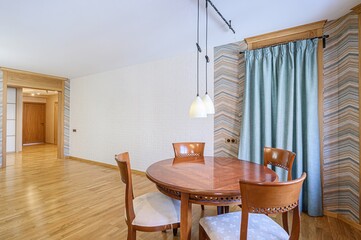 well-lit dining area with a round wooden table, four chairs, a white brick wall, and stylish pendant lights.