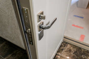 close-up of an open door with a shiny chrome handle and a security lock system.