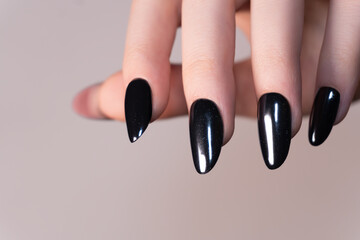 Oval nails with glossy black finish, accented with subtle glitter at the base – a glam-chic manicure with a trendy touch.