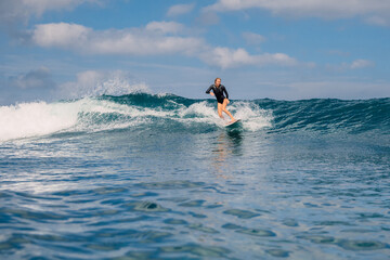 Woman surfer on a perfect blue wave on a sunny day