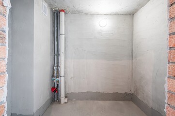 Bare, light-filled room in renovation with exposed concrete ceiling, plastered walls, and smooth...