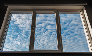 View of blue sky and white clouds thorough window.