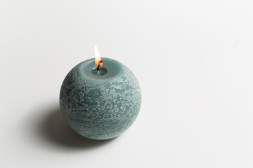 Round candle pf green color on white background.
