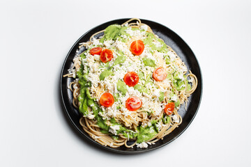 Vegan pasta in black round plate on white background.