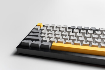 Mechanical keyboard for computer on white background. Key cap of grey, black and yellow colours.