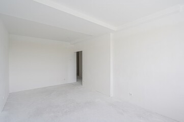 empty, all-white room with a doorway leading to another space. The walls are plain, and the floor...