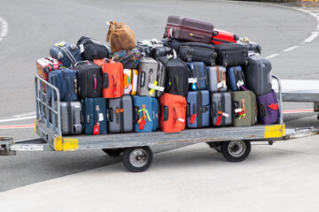 Colorful luggage stacked on airport baggage cart