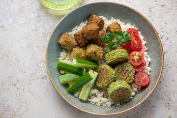 Different types of middle-eastern falafel with couscous and vegetables in a rustic plate,...