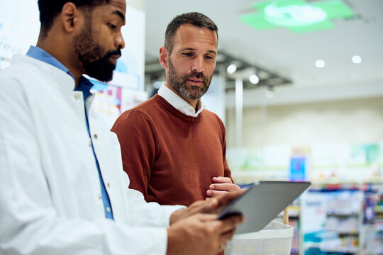 Pharmacist Assisting Customer with Tablet in Modern Pharmacy