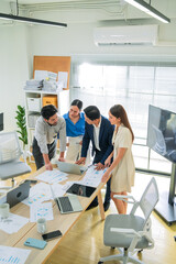 Group of business people reviewing financial charts and laptop insights while standing in office...