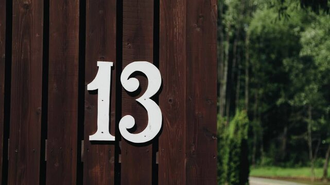 The plate with the number 13 is attached to a wooden fence. The camera captures this number in motion