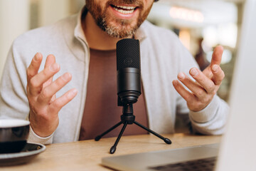 Content creator recording podcast in home studio using professional microphone and laptop