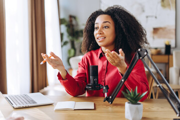 African American young woman recording podcast from home using laptop and a microphone