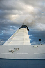ferry boat funnel smoking under a cloudy sky
