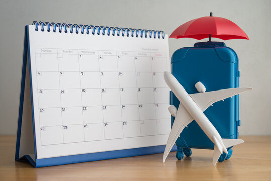 Airplane, suitcase, umbrella and white calendar. Travel holiday or annual leave travel period for relaxation concept. Period of paid time off (PTO) granted to employees by their employer.