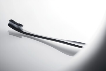 A sleek black toothbrush with soft white bristles rests on a glossy white surface, casting a subtle shadow.