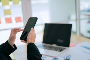 Fototapeta premium Asian businesswomen are confident in the modern workplace, using smartphones for communication and networking.