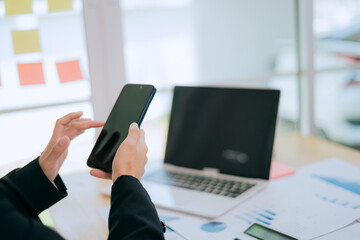Asian businesswomen are confident in the modern workplace, using smartphones for communication and networking.