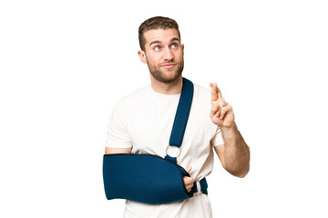 Young handsome blonde man with broken arm and wearing a sling over isolated chroma key background...